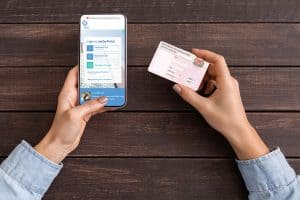 woman's hands holding mobile screen showing the IRAS mytax portal login screen and Singapore NRIC card