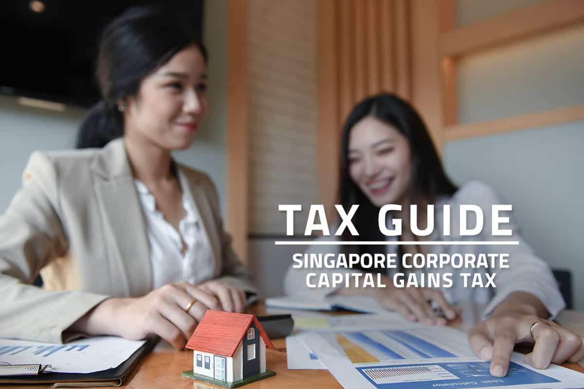 Words Tax Guide Singapore Corporate Capital Gains Tax against background of two asian employees discussing in an office. Accounting documents and a model house on a desk.